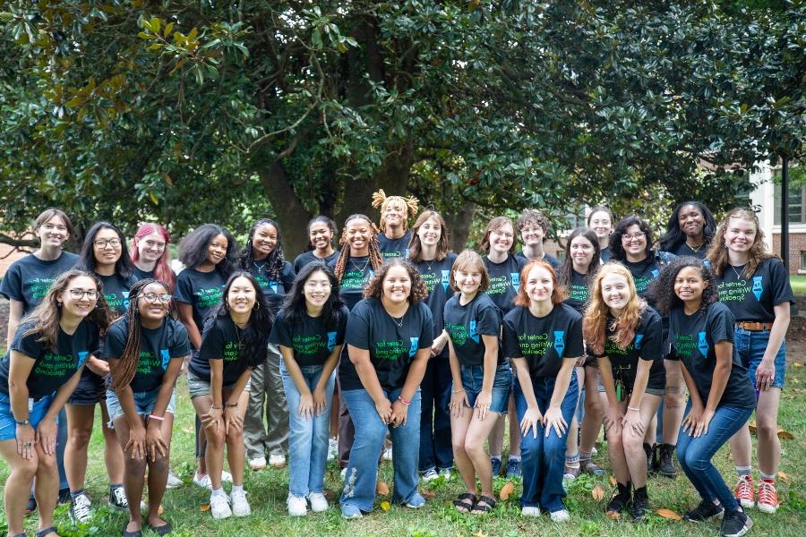 a group of student tutors gather on building stairs wearing the same branded black tee shirts